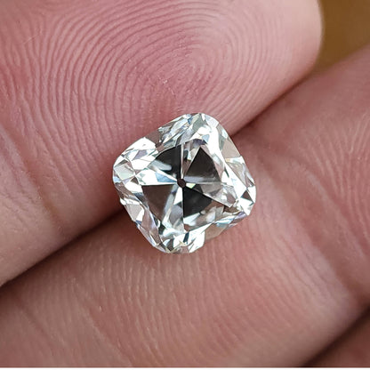 Square cushion cut loose stone shown on fingertips highlighting clear body color and proportions.
