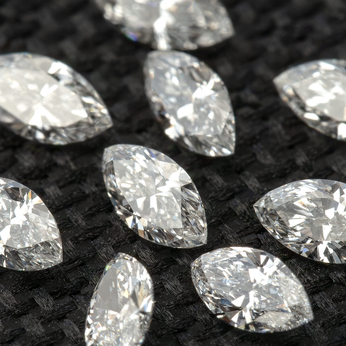 Tilted close-up of loose marquise diamonds, showing pointed ends and changing white and gray reflections.