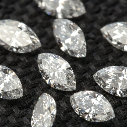 Tilted close-up of loose marquise diamonds, showing pointed ends and changing white and gray reflections.