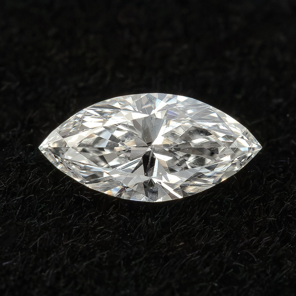 Single marquise diamond on black velvet, seen face-up with broad bright facet reflections.