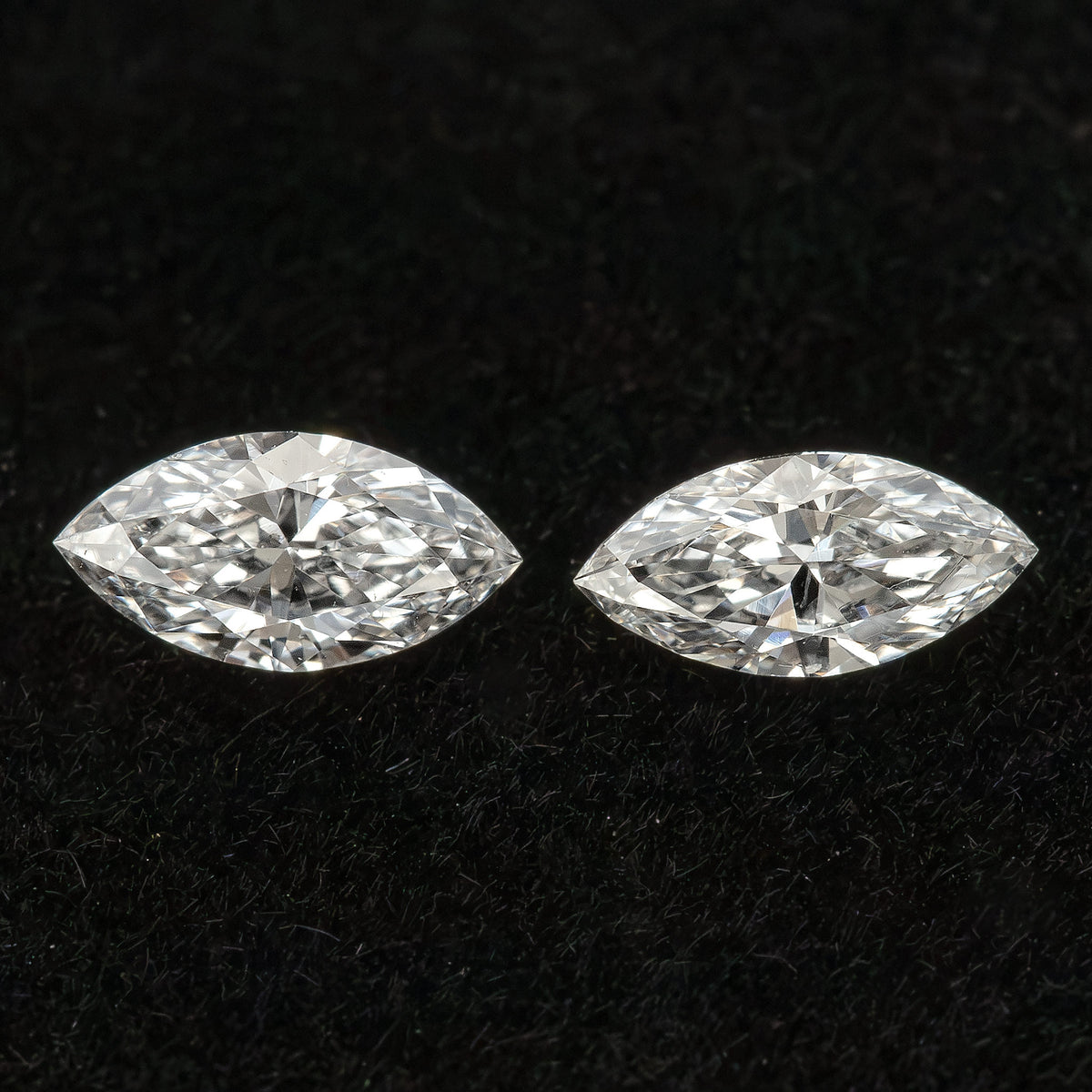 Two marquise diamonds separated on black velvet, illustrating a pair rather than a larger parcel.