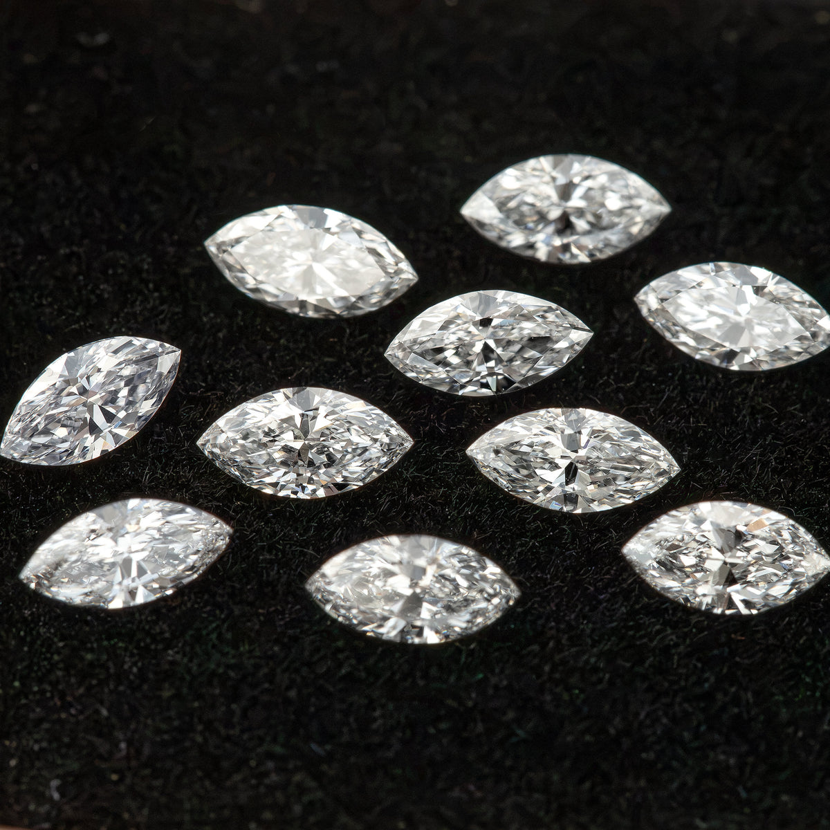 Ten white marquise diamonds spread across black velvet as a reference for the calibrated supply.