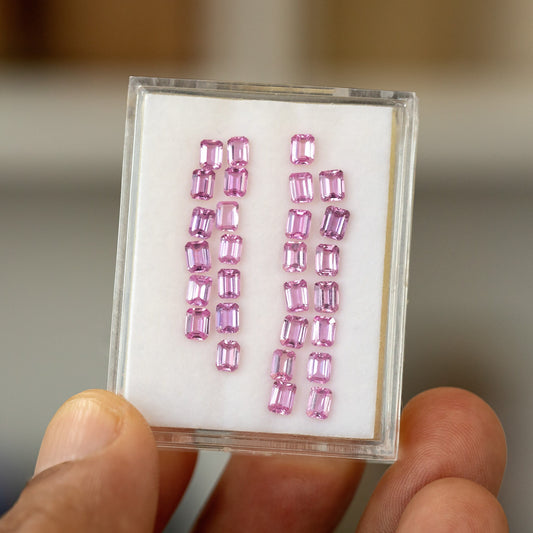 Full representative parcel of pink emerald-cut sapphires in a hand-held white display tray; one random sapphire is supplied per purchase.