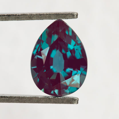 Pear sample held upright in tweezers, with the pointed end at the top and crown facets visible.