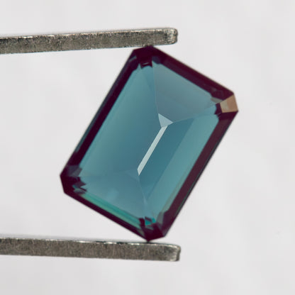 Pavilion-facing rectangular sample in tweezers, showing the back facet structure.