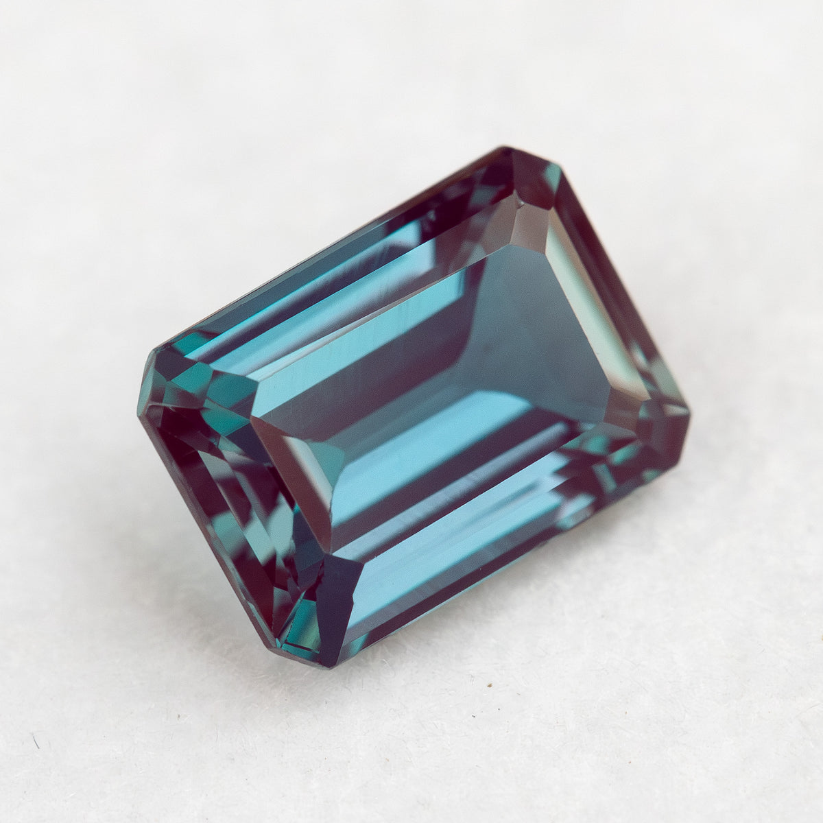 Angled crown view of the rectangular sample with blue-green reflections across its step facets.