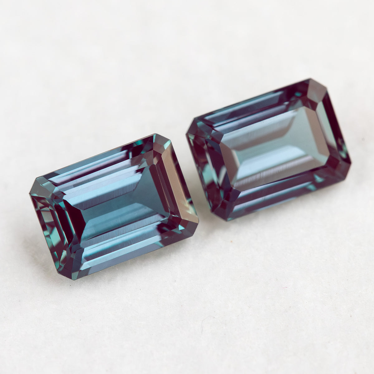 Two crown-facing emerald-cut lab-grown alexandrite samples in a diagonal arrangement, illustrating the pair purchase option.