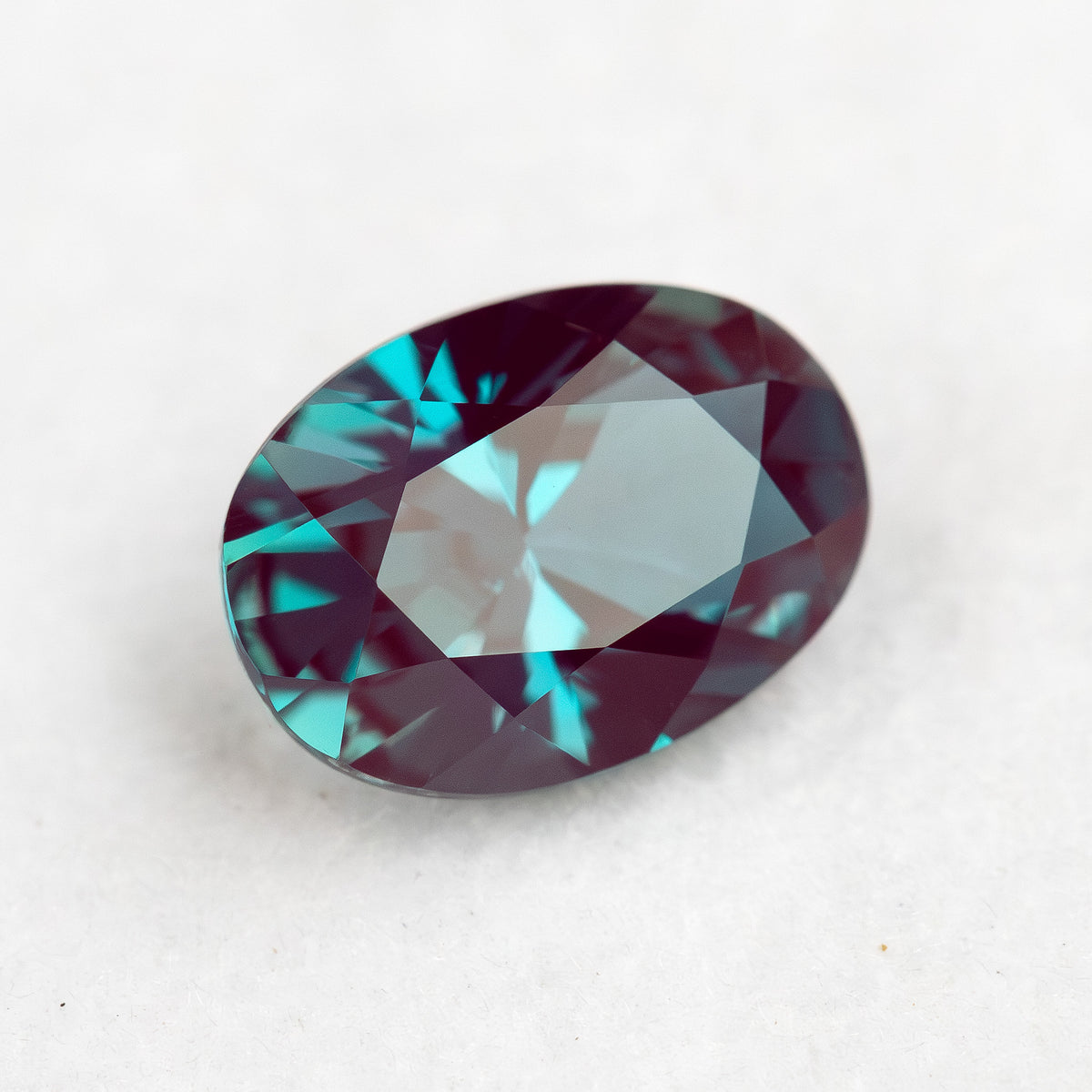 Tilted crown view of the oval sample with a broad pale reflection across its table.