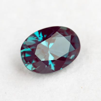 Tilted crown view of the oval sample with a broad pale reflection across its table.