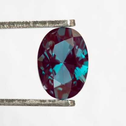 Oval sample held upright in tweezers, with its crown facing the viewer.