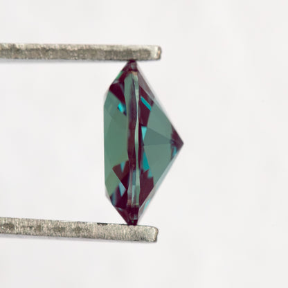 Side profile of the oval sample between tweezers, showing crown and pavilion depth.