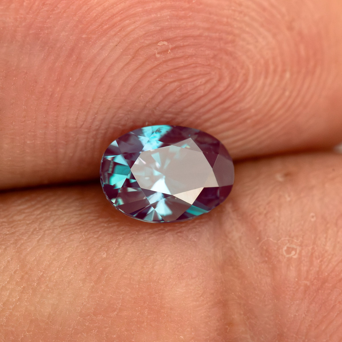 Oval sample resting on fingertips to show its scale and reflected light.