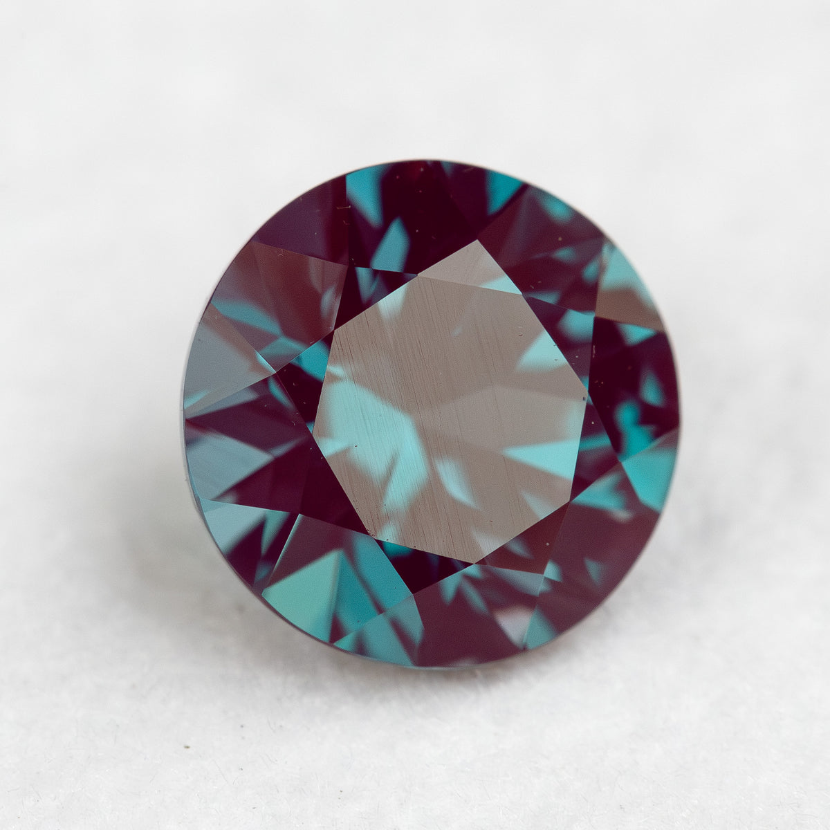 Angled crown view of a round sample on a pale surface, showing changing table reflections.