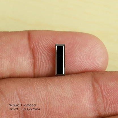 Reference black baguette diamond face-up between fingertips, showing its dark rectangular table and straight stepped edges.