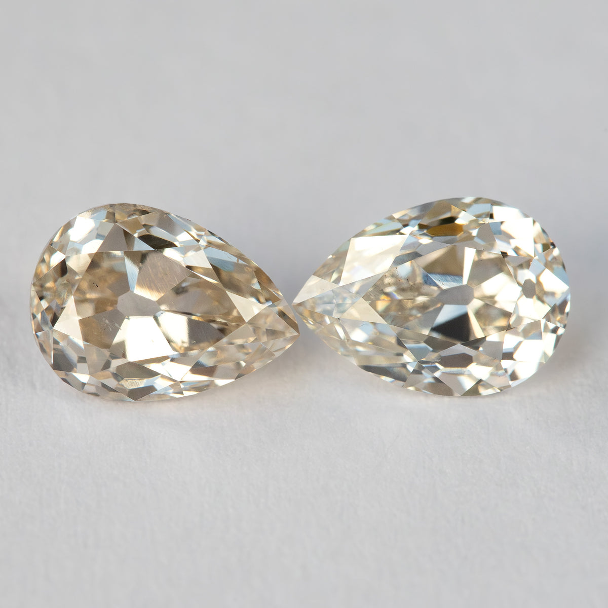 Vista frontal emparejada de los dos diamantes con sus puntas orientadas hacia adentro, mostrando diferencias en el contorno y el patrón de facetas.