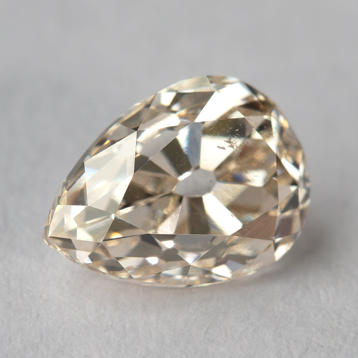 Alternate face-up view of the pear-cut diamond on a light background, showing the antique-style facet pattern.