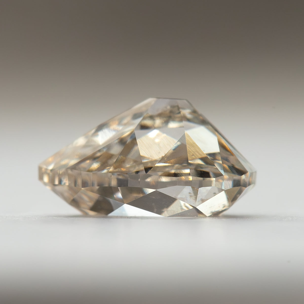 Side-profile view of the lab-grown diamond on a light surface, showing its crown and pavilion depth.
