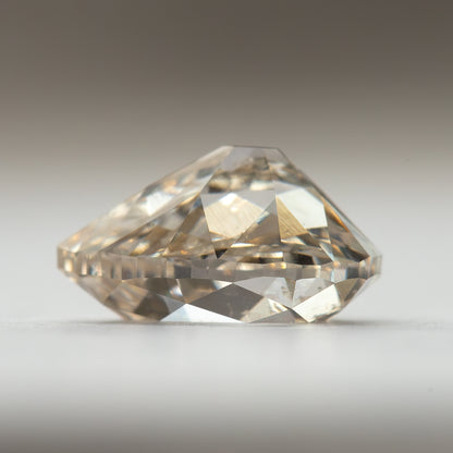 Side-profile view of the lab-grown diamond on a light surface, showing its crown and pavilion depth.