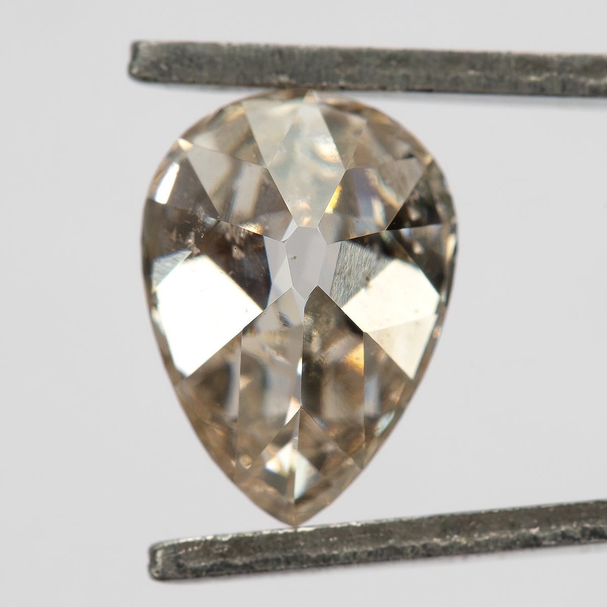 Pavilion view of the exact pear diamond held in tweezers, showing its back facet arrangement.