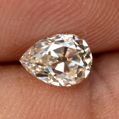 The pear-cut diamond resting on a fingertip, providing a close hand-scale view.