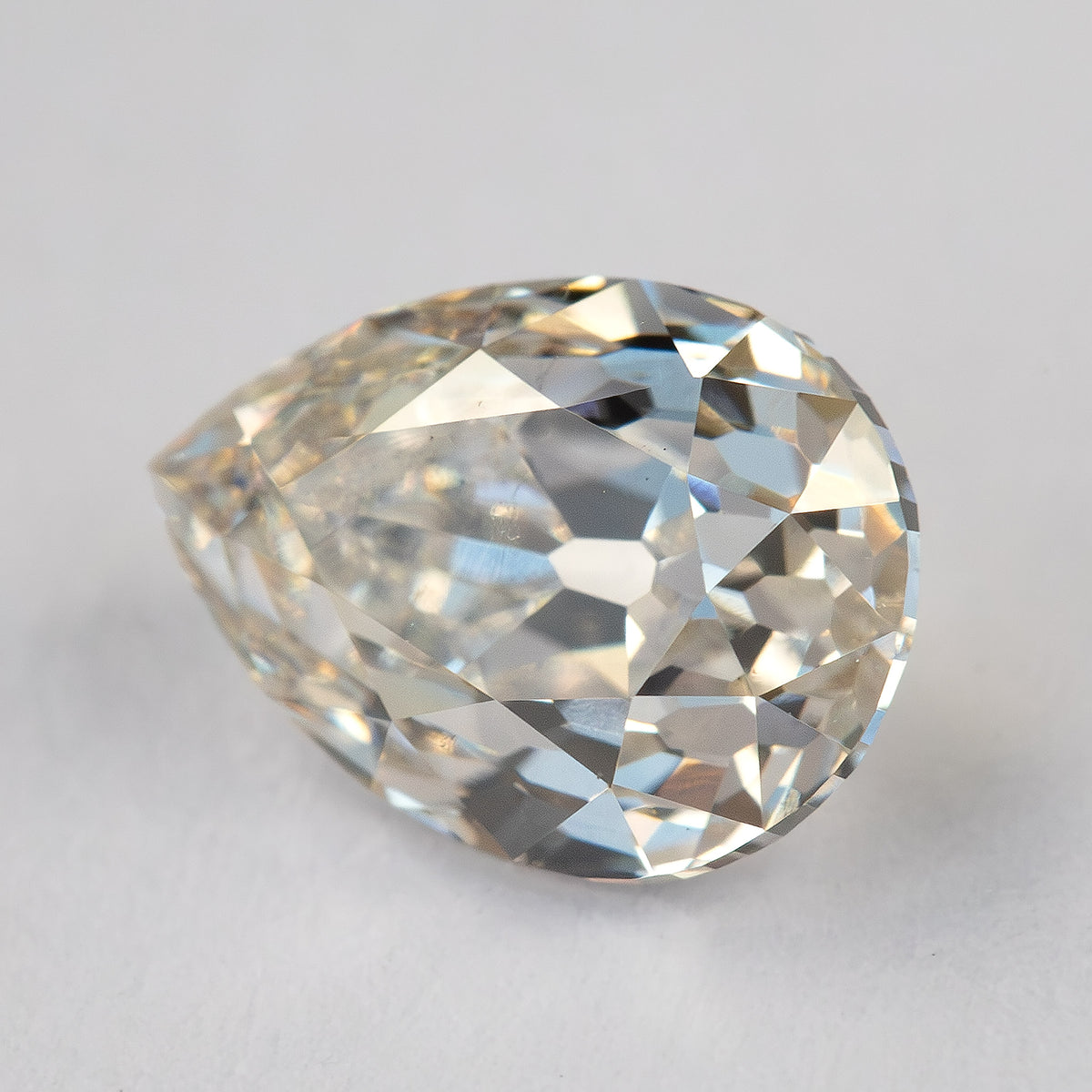 Angled face-up view of the exact diamond on a light surface, showing its rounded shoulders and pointed tip.