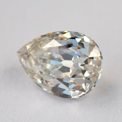 Angled face-up view of the exact diamond on a light surface, showing its rounded shoulders and pointed tip.