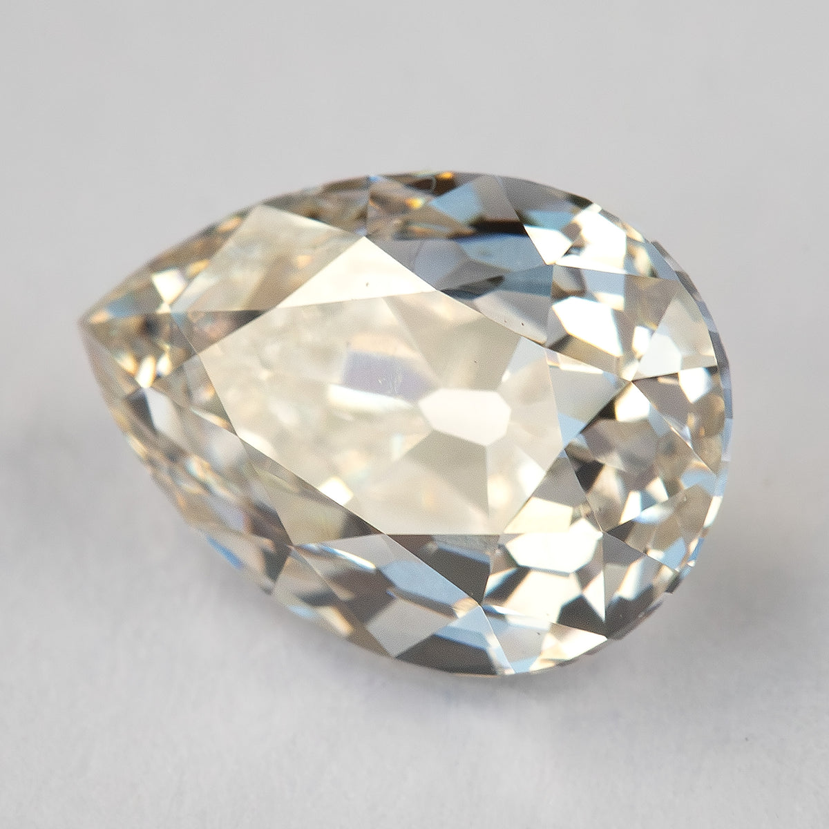 Three-quarter face-up view of the pear-cut diamond, showing warm reflections and visible internal features.