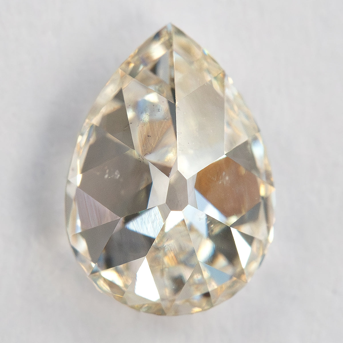 Pavilion-side view of the exact pear diamond on a light surface, showing back facets and inclusions.