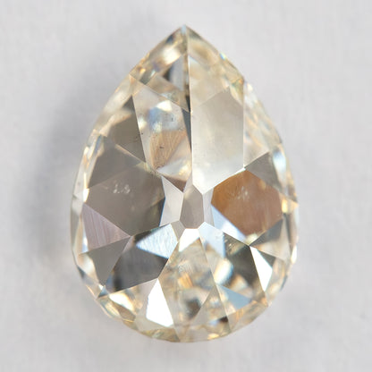 Pavilion-side view of the exact pear diamond on a light surface, showing back facets and inclusions.