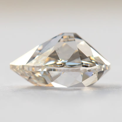 Side-profile view of the pear-cut diamond on a light surface, showing its crown, girdle and pavilion depth.
