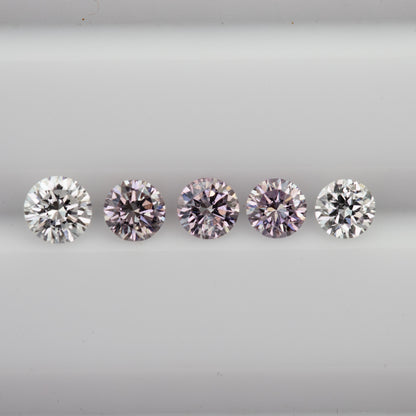 Horizontal face-up row of pink round diamond samples with white color-reference diamonds at both ends.