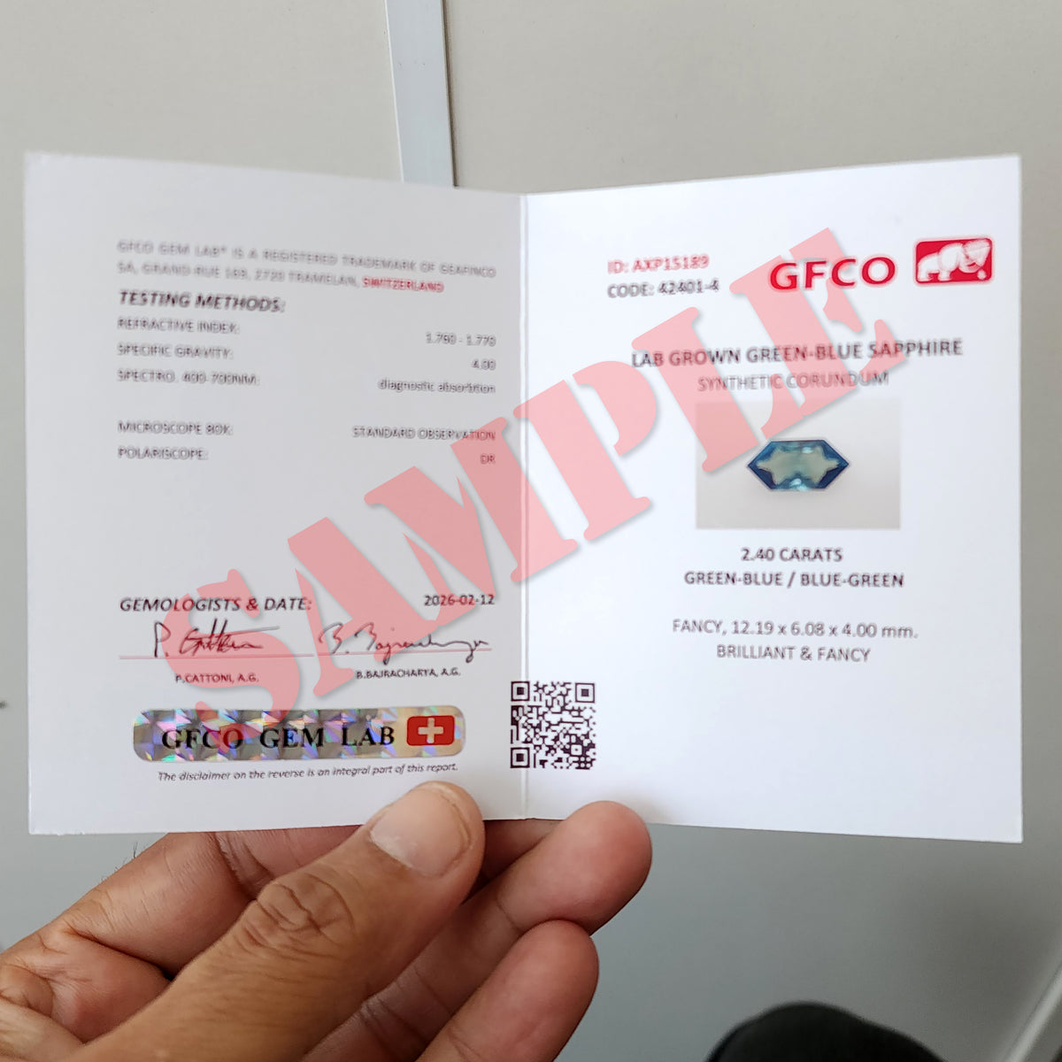 Open GFCO Gem Lab report held in a hand, with a prominent SAMPLE watermark across the pages.