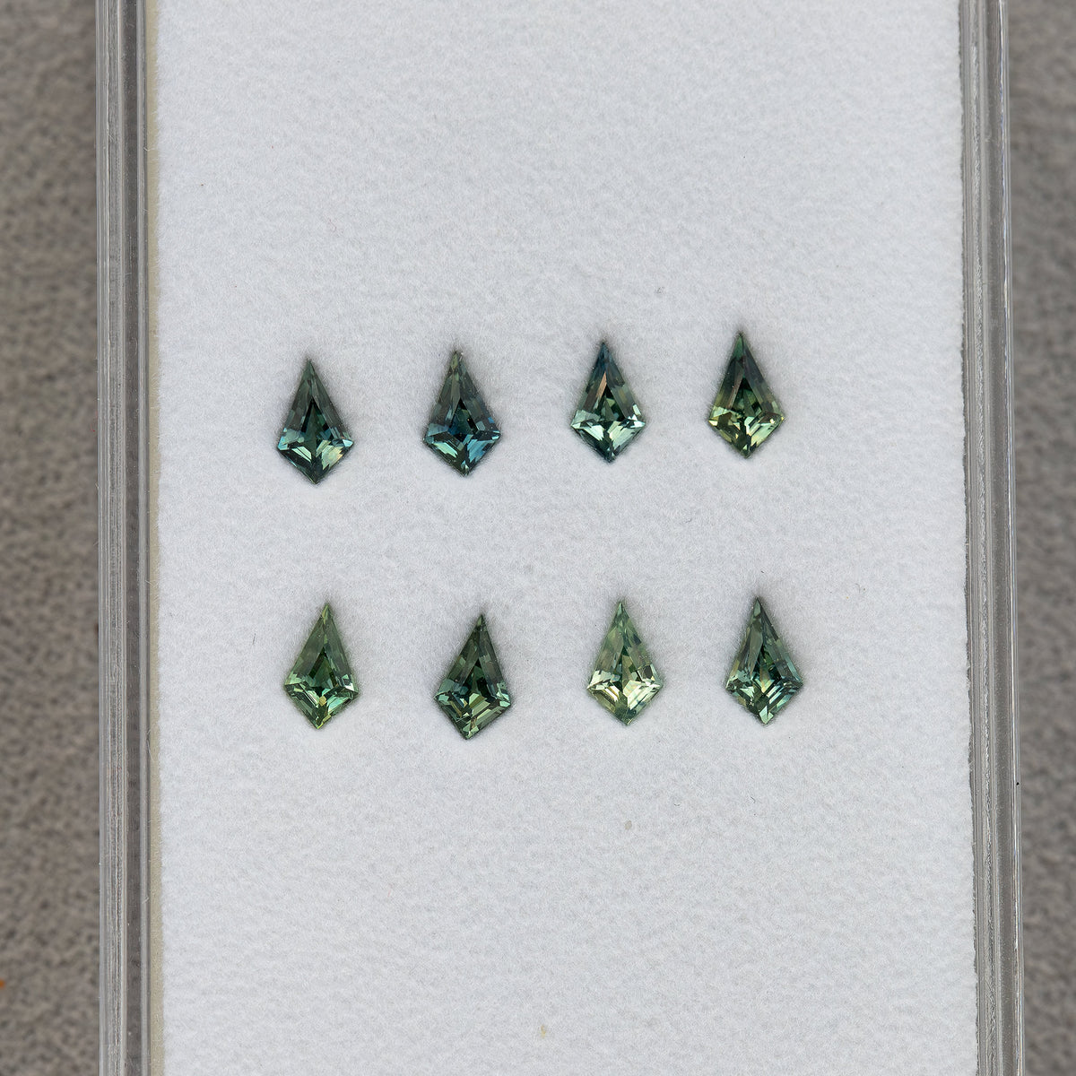 Eight kite sapphires arranged in two rows inside a gem tray.
