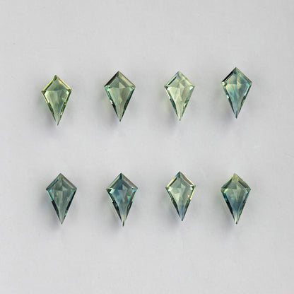 Pavilion-side view of the original eight kite sapphires on a pale surface.