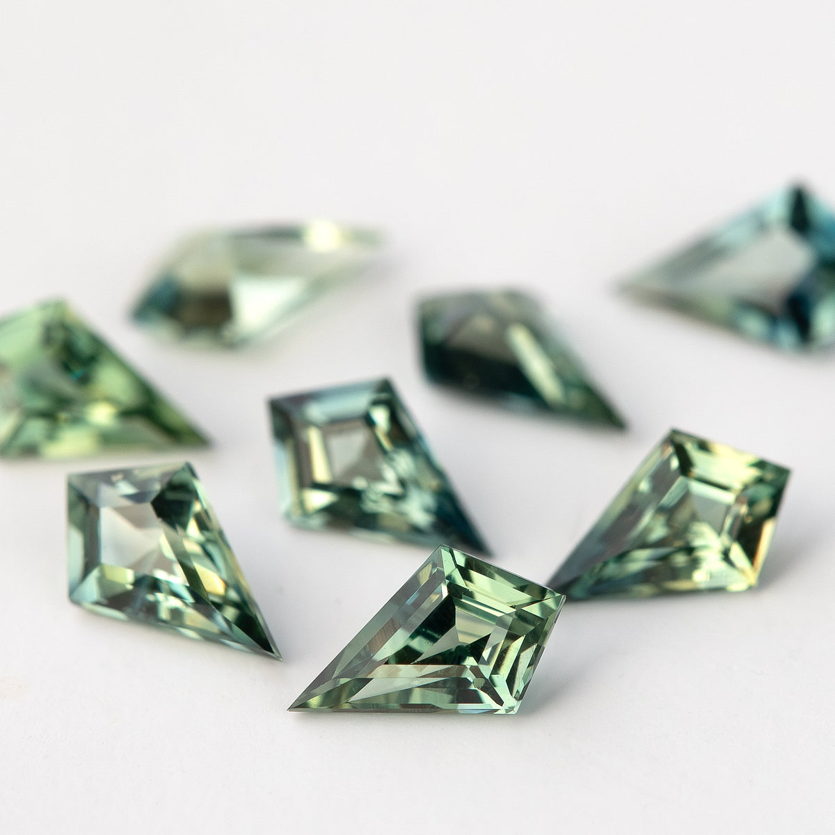 Low-angle sapphire group view with several bright green facet reflections.