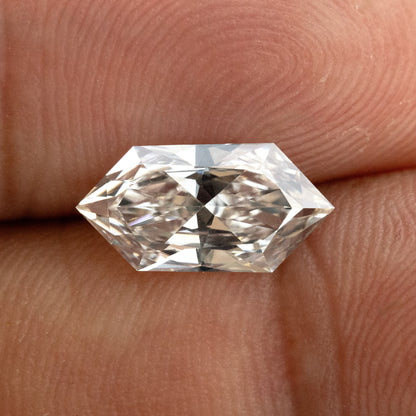 Horizontal macro shot of an elongated geometric hexagon diamond showing facet pattern against finger skin.