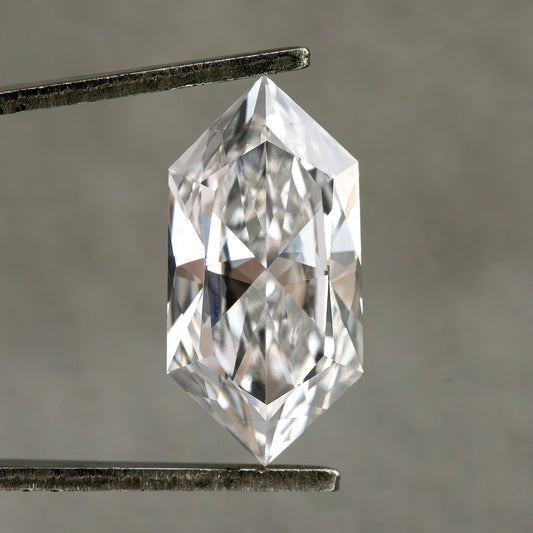 Studio face-up view of an elongated hexagonal diamond held vertically in tweezers on neutral gray background.