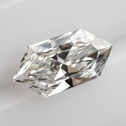 Oblique angle showing facet structure and depth of an elongated hexagon cut gemstone on a white grooved surface.