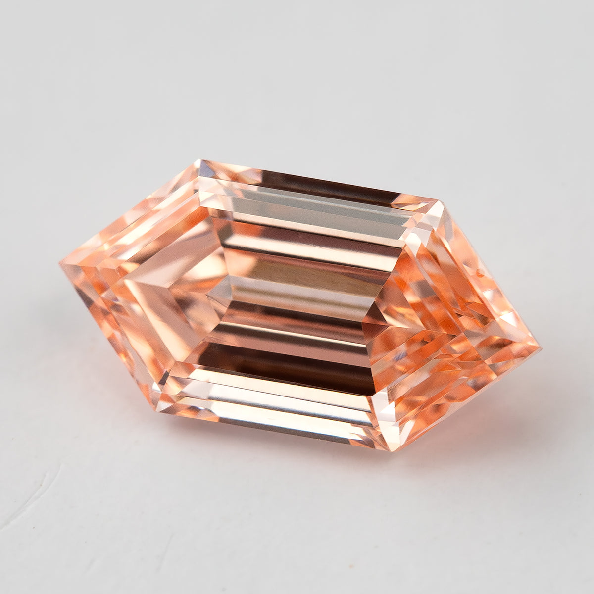 Close angled view showing broad step facets and pinkish orange flashes across the lab-grown diamond.