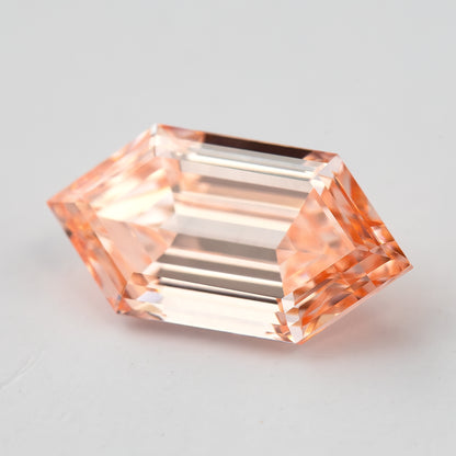 Bright angled view showing the diamond's transparent step pattern and peach pinkish orange appearance.