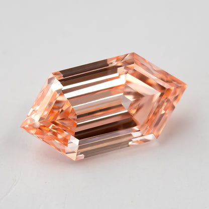 Angled face-up view of the loose diamond showing its elongated six-sided outline and warm peach tone.