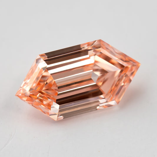 Angled face-up view of the loose diamond showing its elongated six-sided outline and warm peach tone.