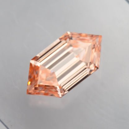 Three-quarter view of the loose diamond showing peach color, pointed corner facets and depth.