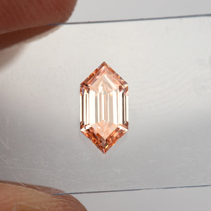 Small face-up view between fingers showing the scale of the 8.52 by 4.32 mm loose diamond.