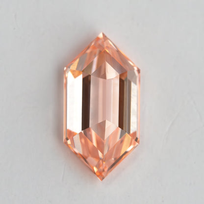 Pavilion-side view of the peach pinkish orange lab-grown diamond, showing its elongated keel and reverse facet geometry.