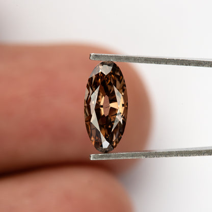 1.43 ct pinkish-brown lab-grown elongated oval diamond, finger scale in tweezers, SKU BLD154