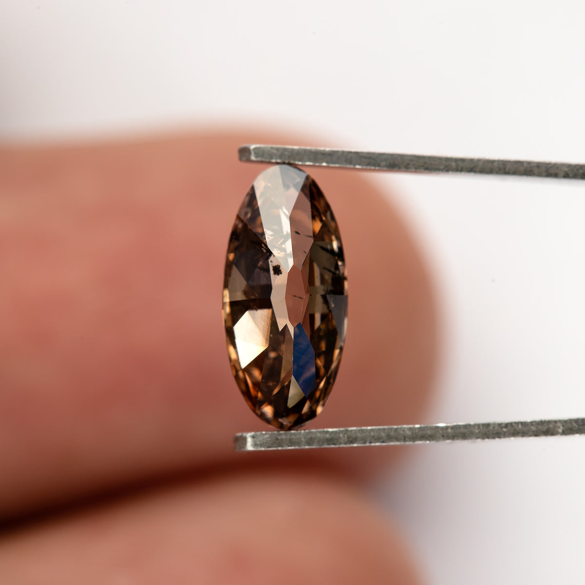 1.43 ct pinkish-brown lab-grown elongated oval diamond, side scale in tweezers, SKU BLD154