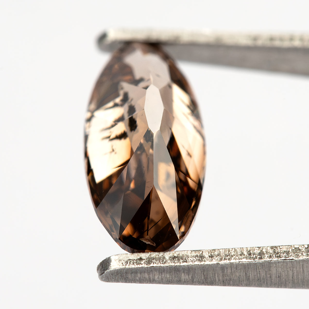 1.43 ct pinkish-brown lab-grown elongated oval diamond, bright view in tweezers, SKU BLD154