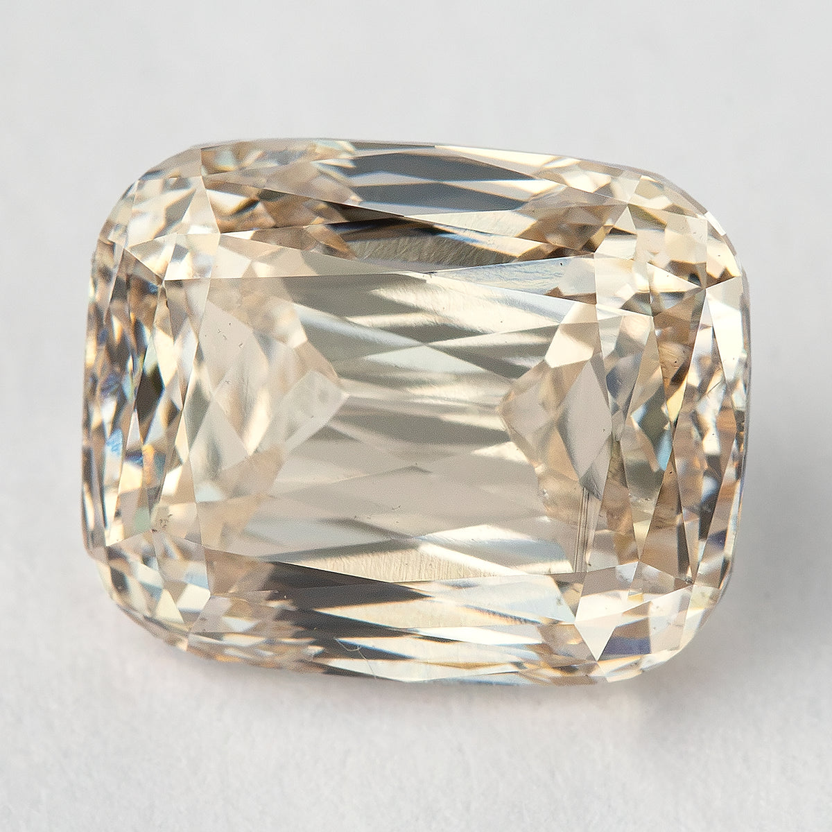 Face-up view of the elongated cushion diamond resting on a light background, showing its outline and crossed modified-brilliant facet pattern.