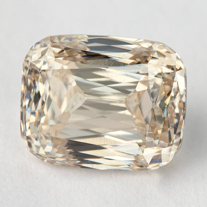 Face-up view of the elongated cushion diamond resting on a light background, showing its outline and crossed modified-brilliant facet pattern.